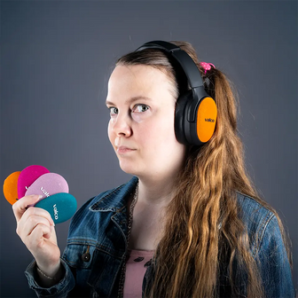 Person wearing black Valco VMK25.2 headphones with an orange Skin cover and holding Skins in several colors